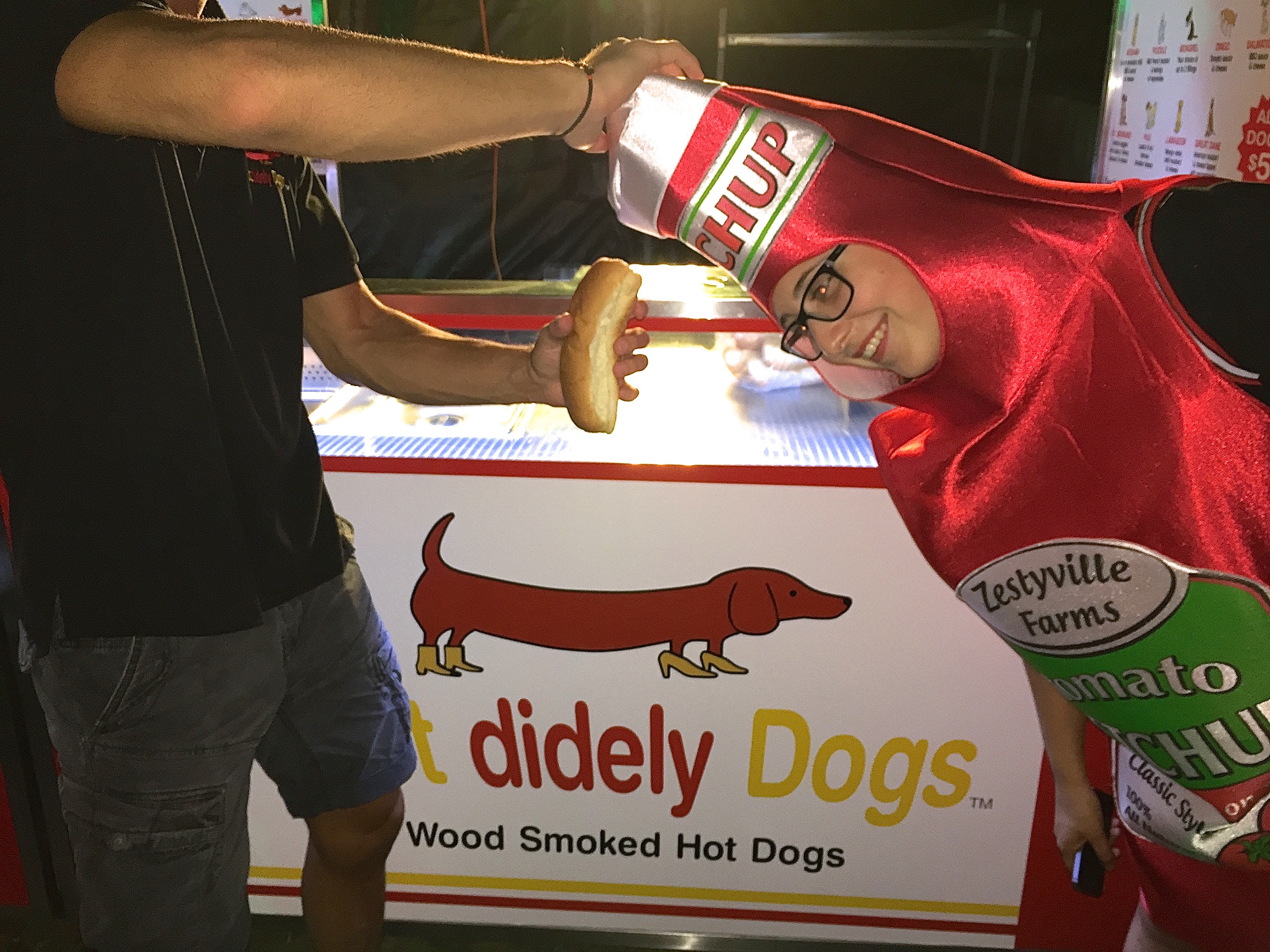 The custom-built stainless steel modular hot dog cart with branded signage in a garden setting